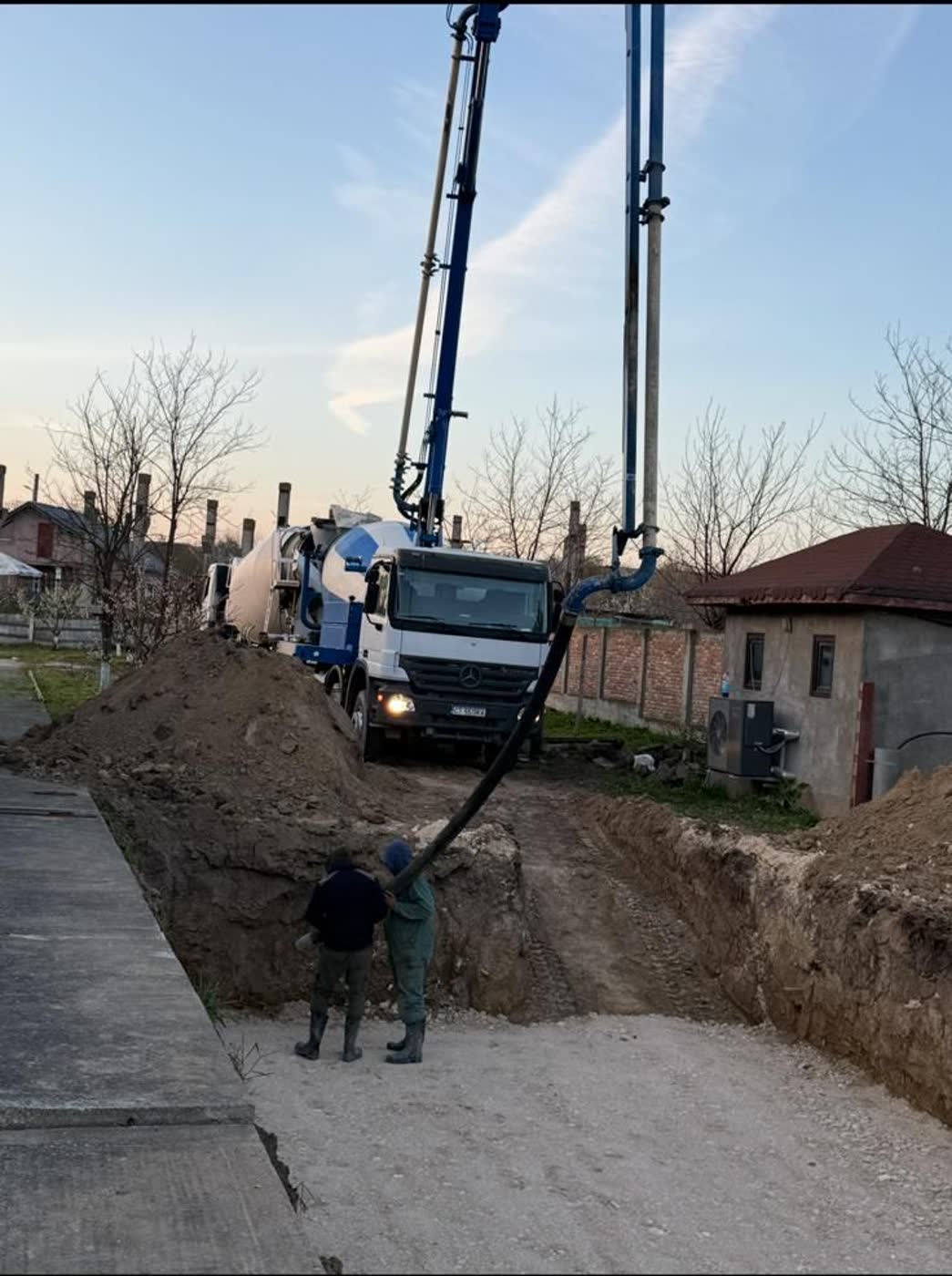 Pompare de beton într-o săpătură, pe o stradă îngustă